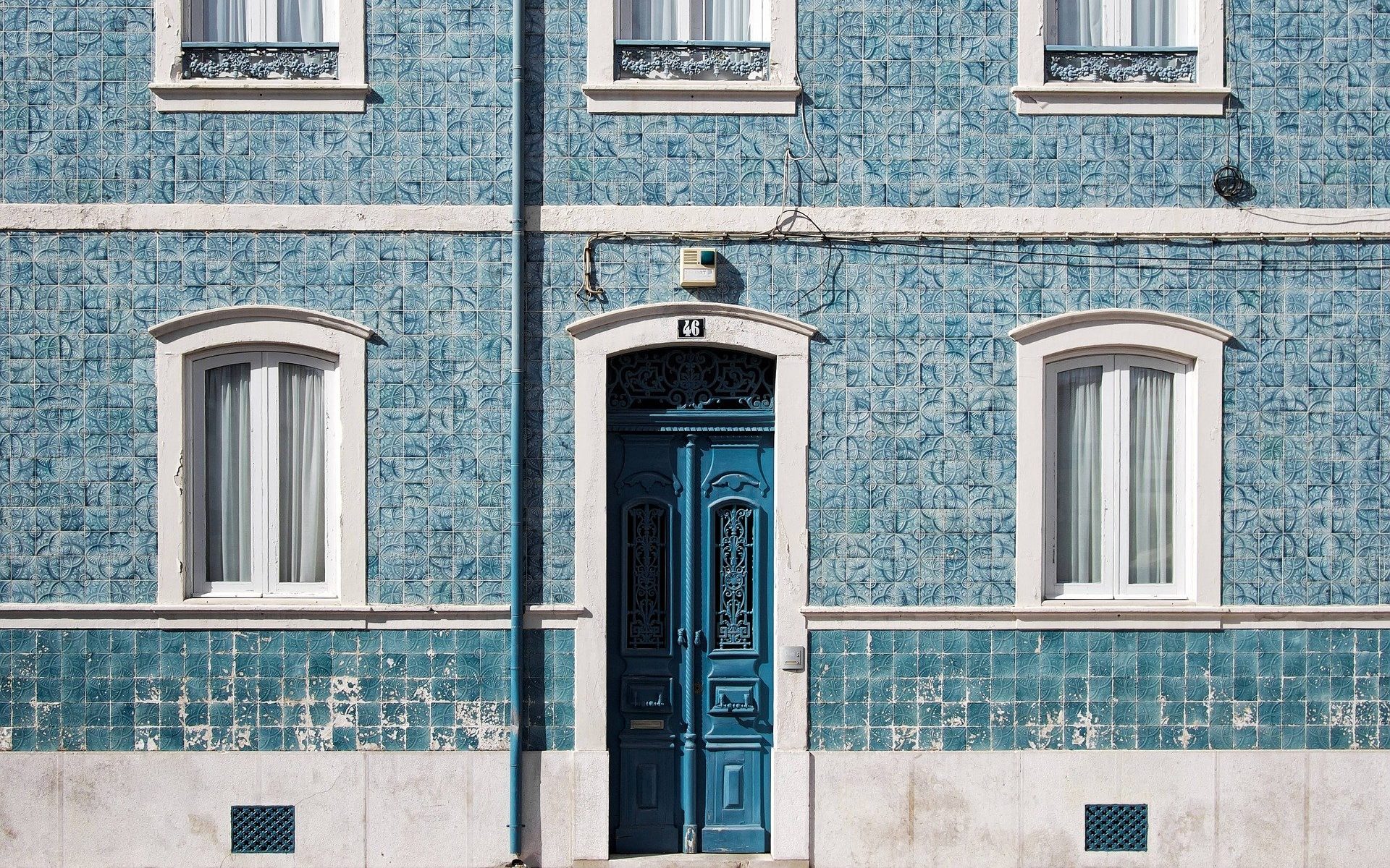 Altes Gebäude mit verzierter Fassade und geschlossener Holztür.